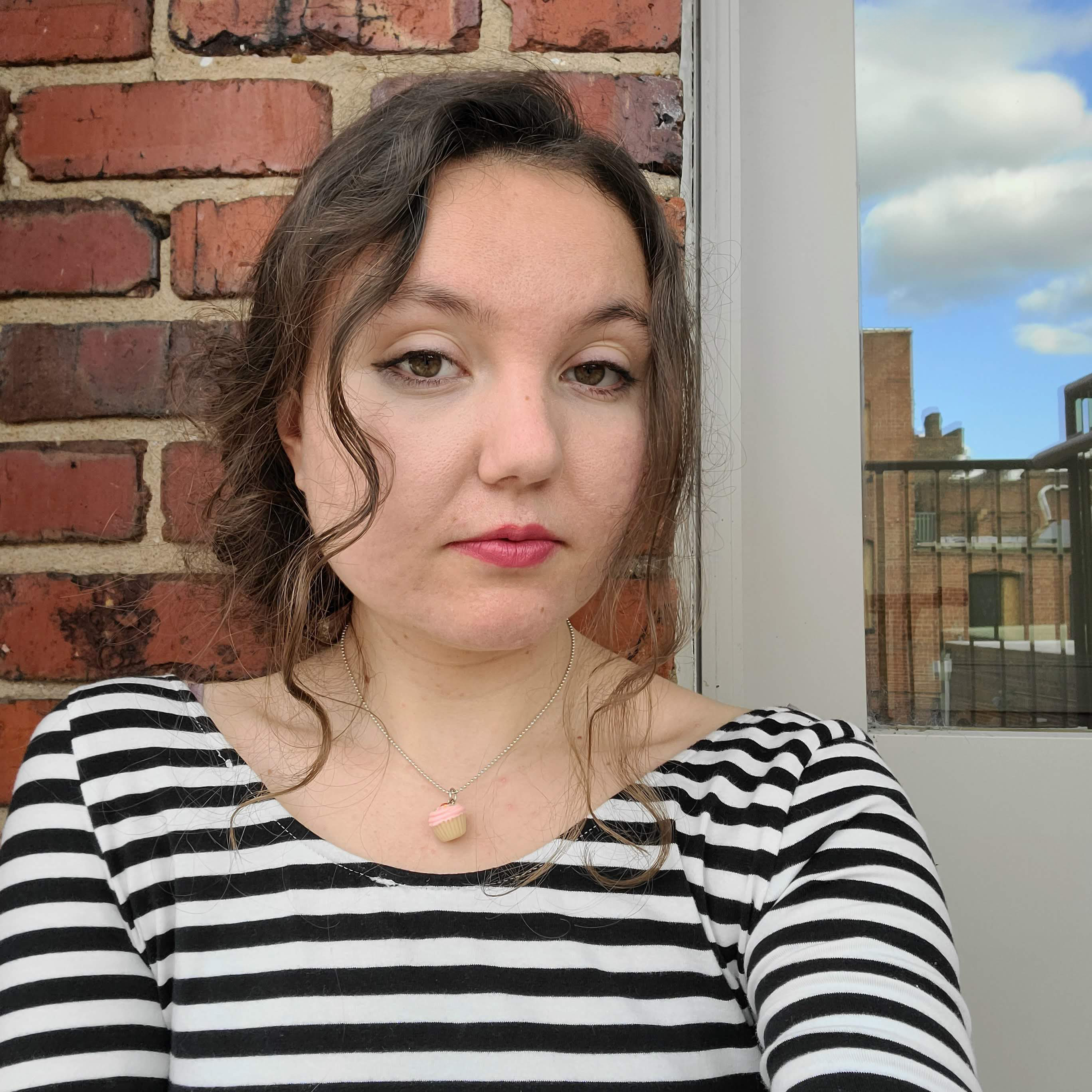 headshot of woman with brick wall backdrop